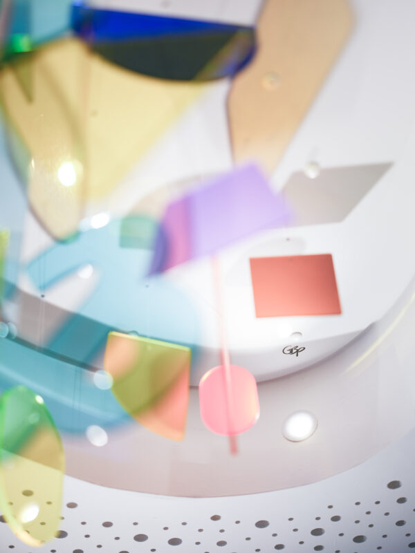 Mobile mit Elementen aus Plexiglas in Pastelltönen schweben durchs Bild